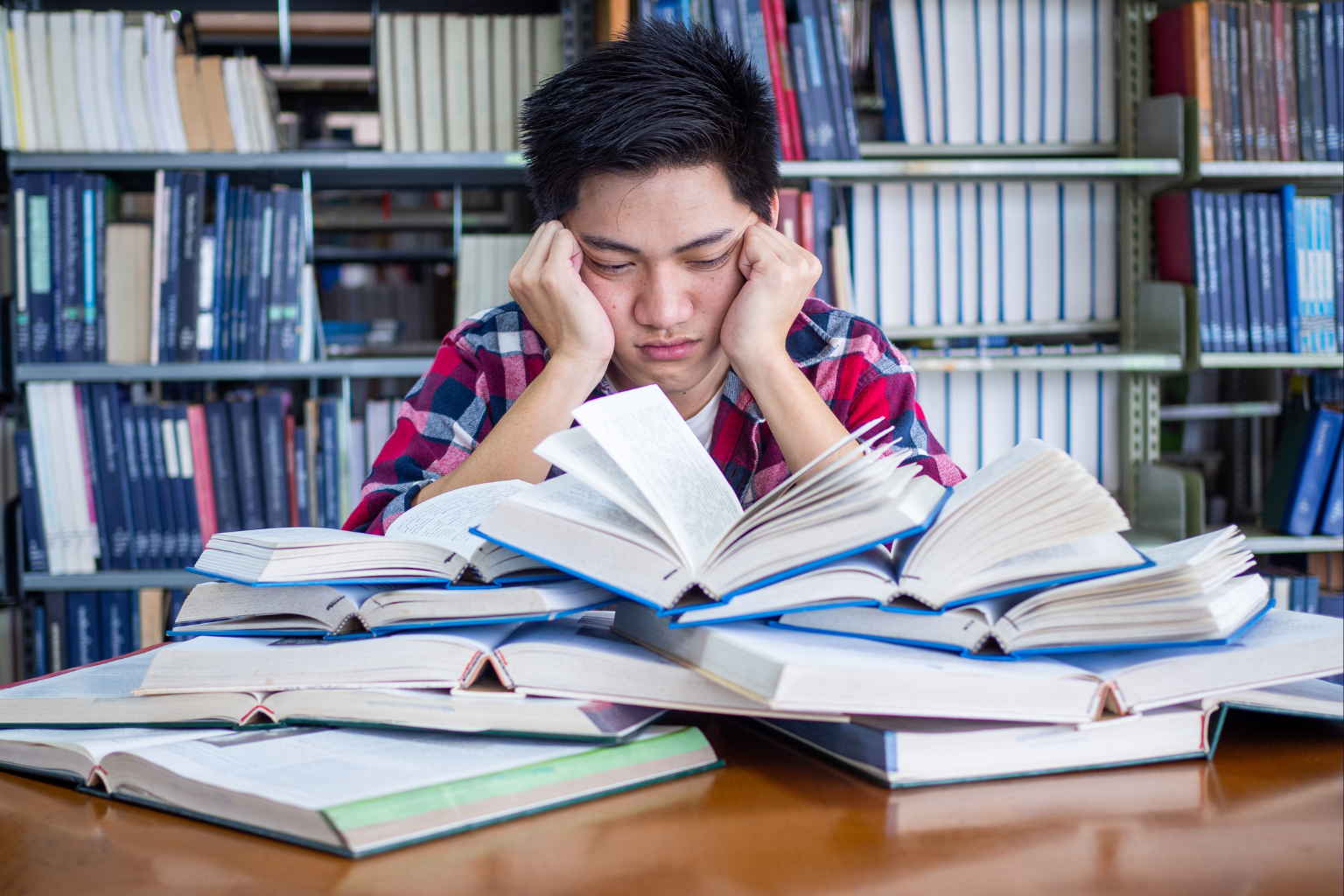 College Student Frustrated Over Books College student frustrated looking down on a pile of books.