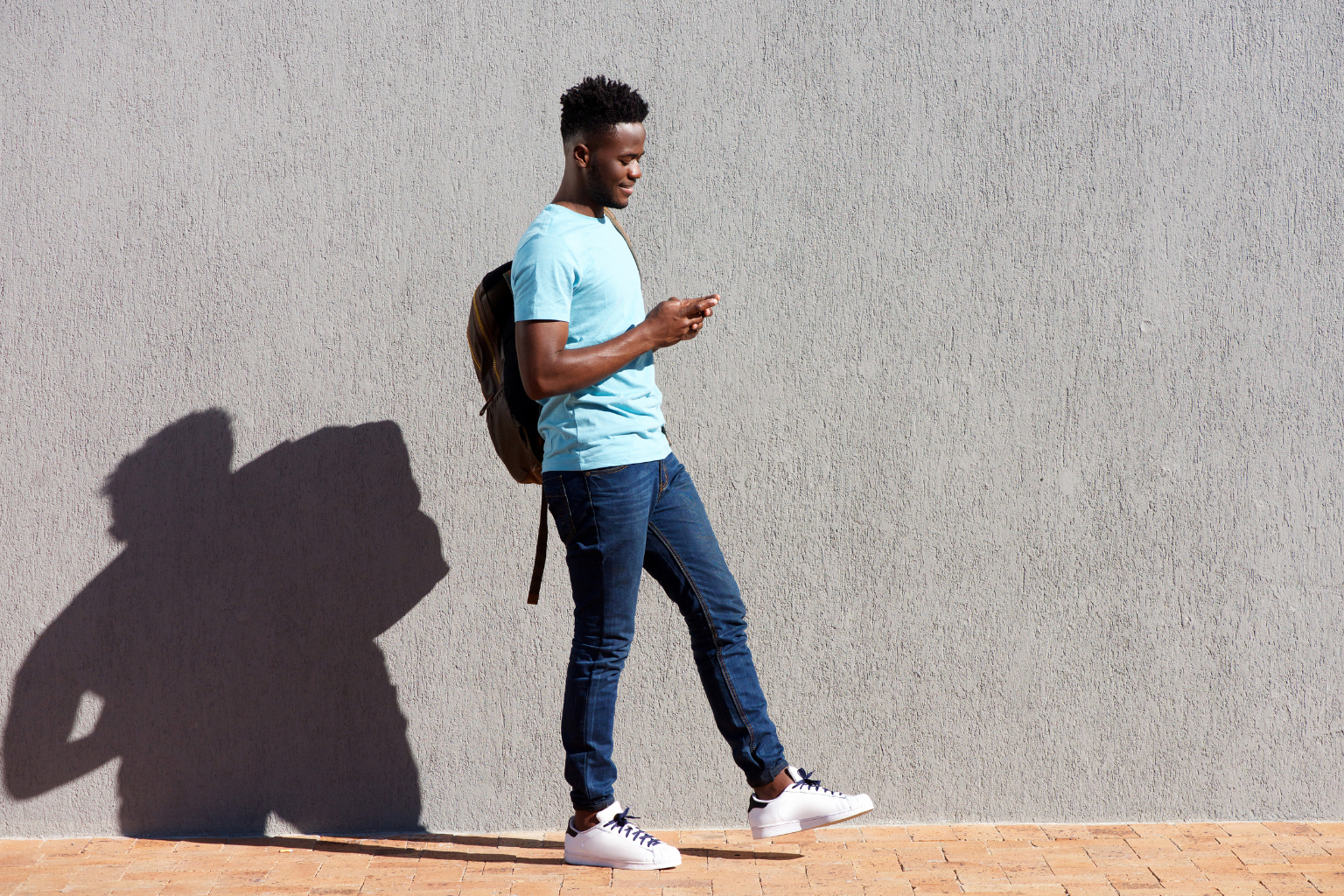 Student on phone taking assessment black student on mobile phone with shadow against wall