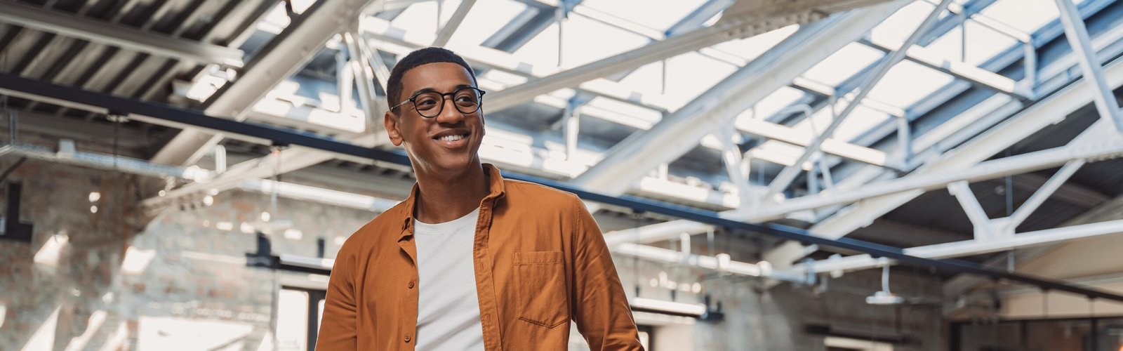 Young,Smiling,Freelancer,Standing,On,Coworking,Background,And,Looking,At