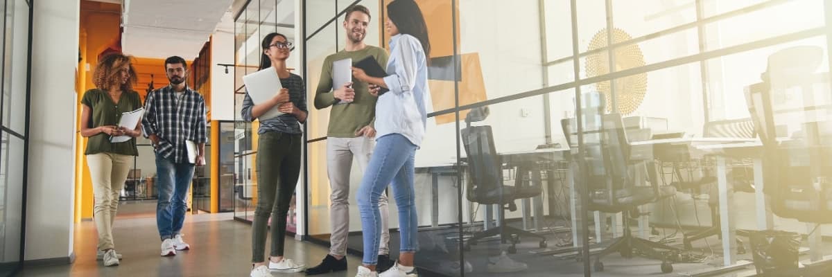office workers collaborating on projects and talking in hallway after team development workshop